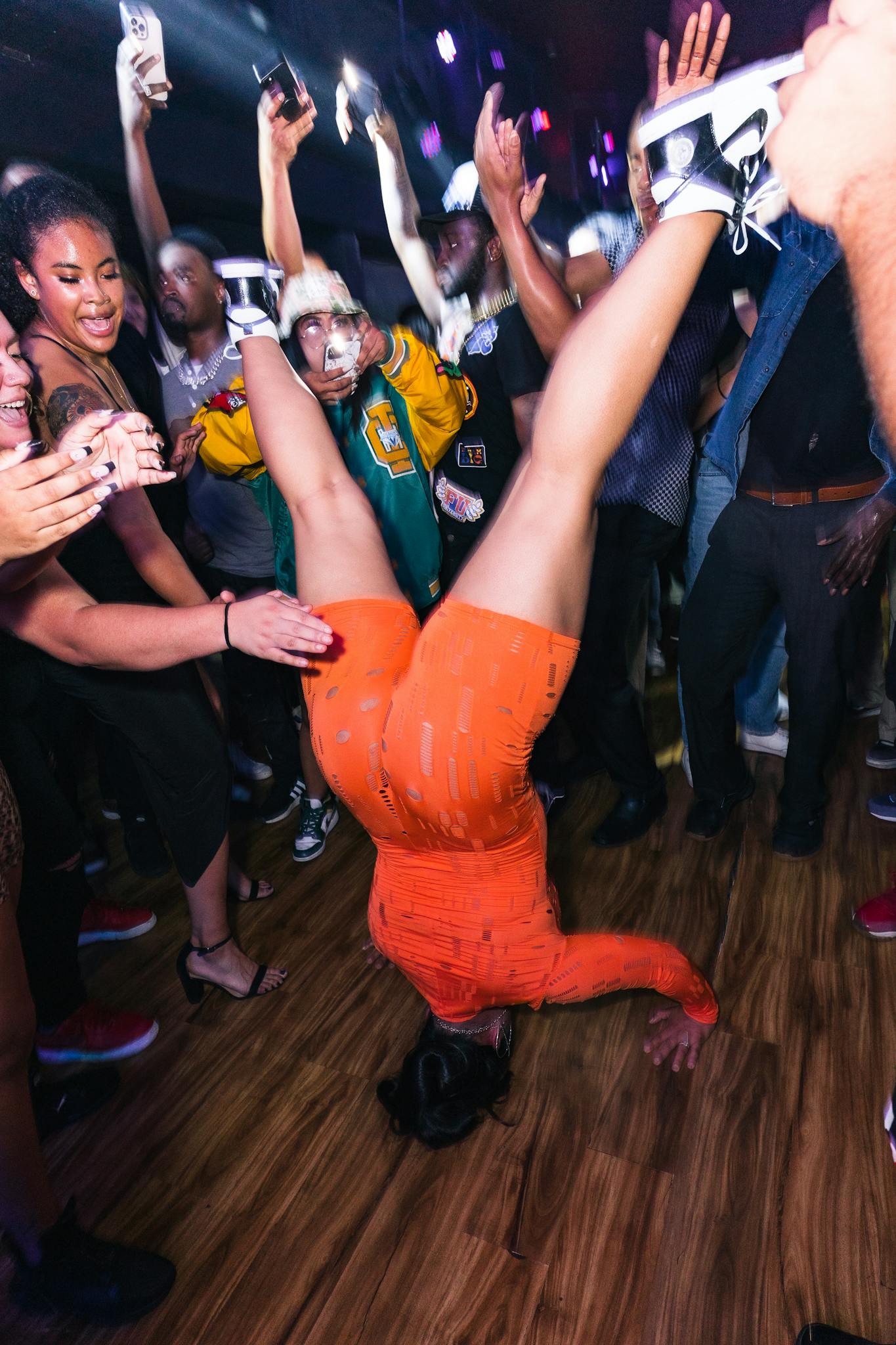 A lively nightclub scene with a dancer performing a headstand on the dance floor.