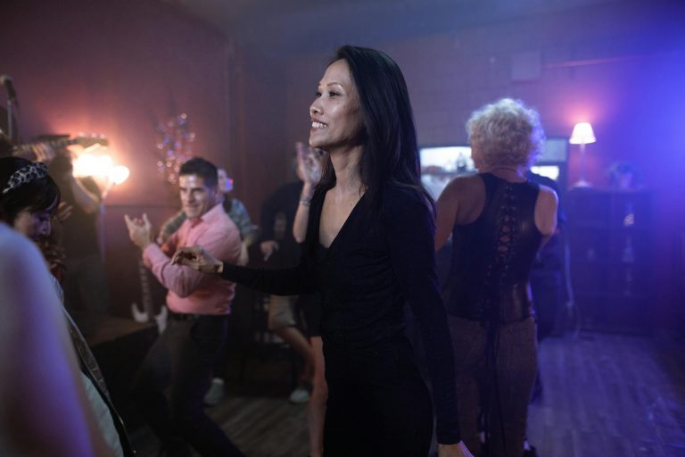 Energetic adults enjoying a lively night out at a club, dancing with joyous expressions.
