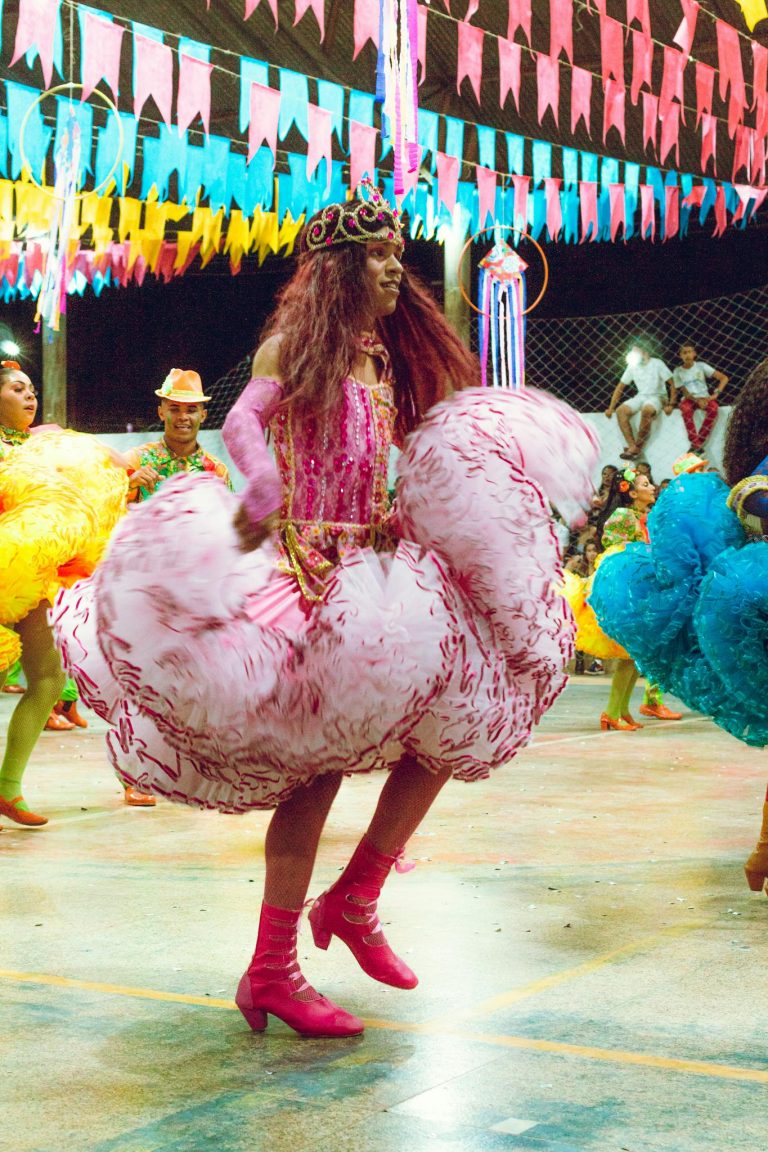 Festive dance scene with colorful costumes and decorations indoors at night.