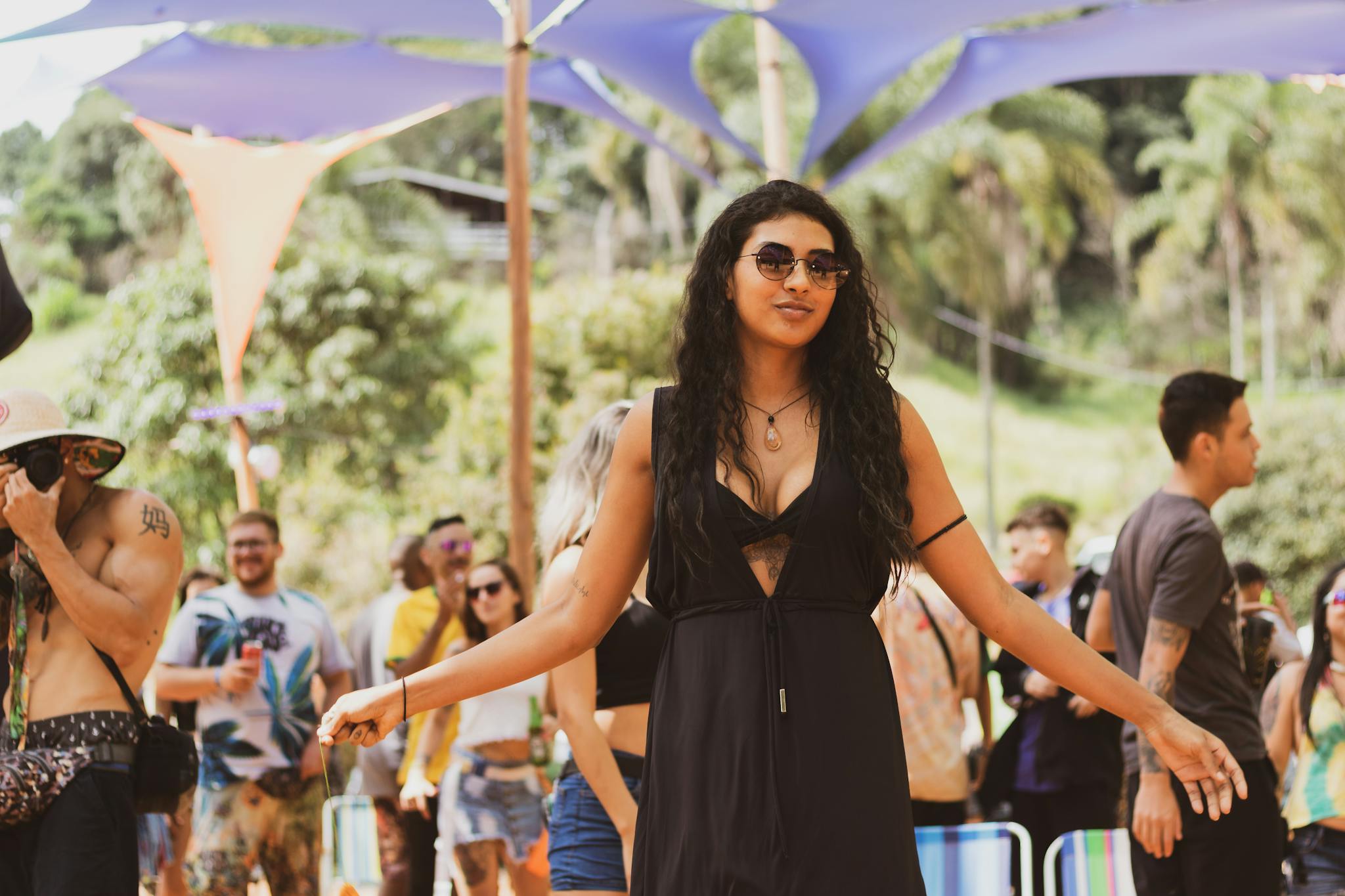 Lively outdoor festival capturing diverse attendees enjoying music and dancing under colorful canopies.
